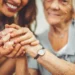 caregiver and elderly woman holding hands