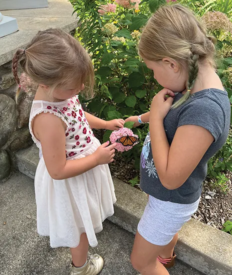 two girls looking at butterfly