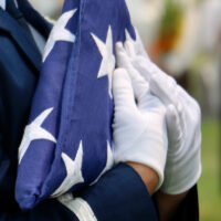 Uniformed male carrying folded American flag