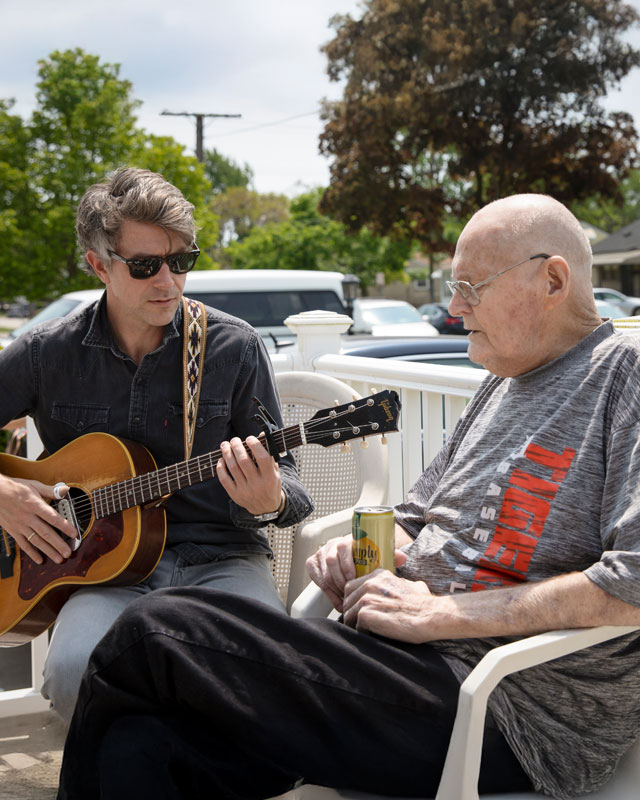 Music therapist playing guitar for gentleman